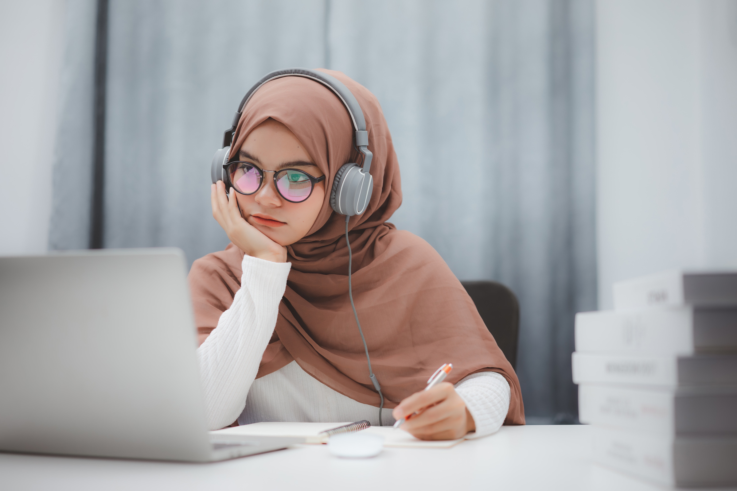 Beautiful muslim student girl using a laptop computer learning online at home. Distance learning online education.